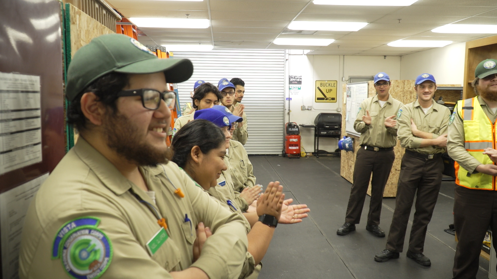vista corpsmembers standing in a warehouse receiving a briefing