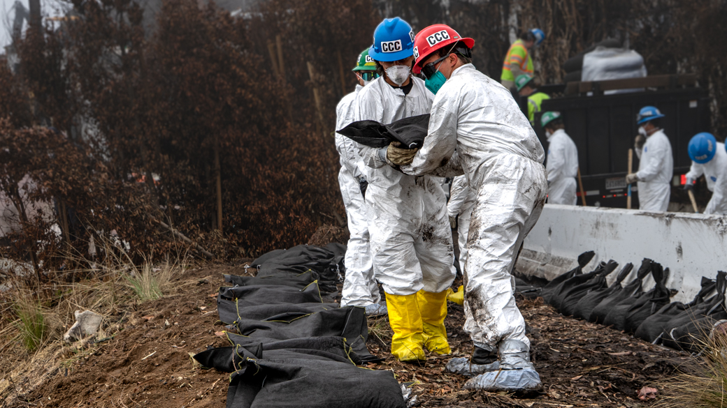 Corpsmembers chain sandbags in a burnt Pacifc Palisades neighborhood. 