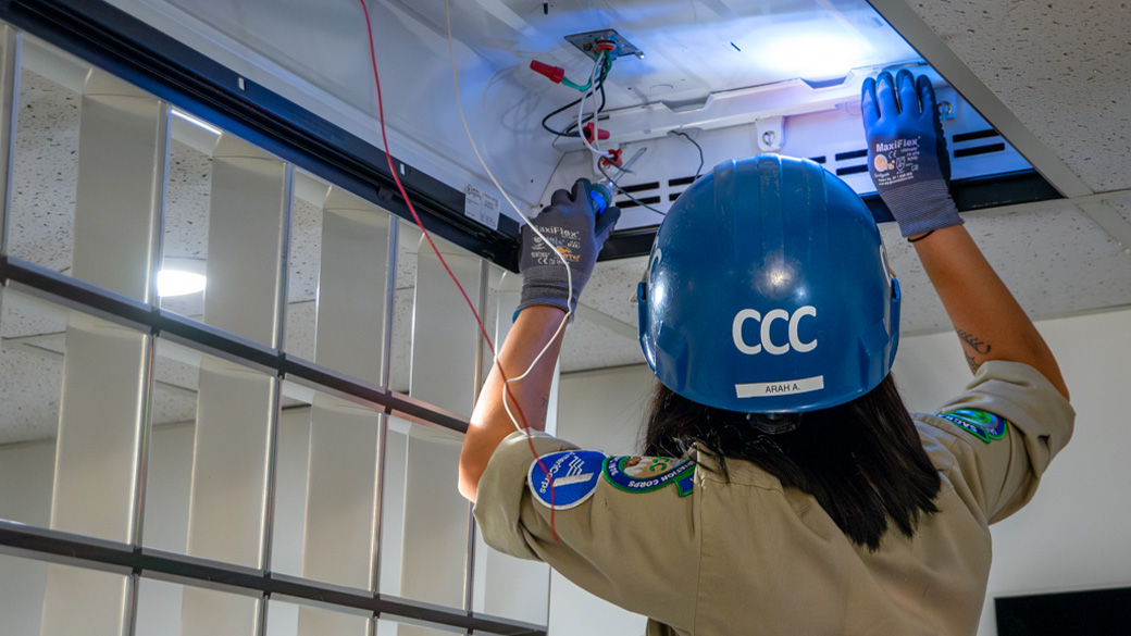 female in helmet has hands in a light fixture