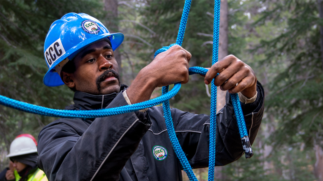 corpsmember in helmet tying ropes