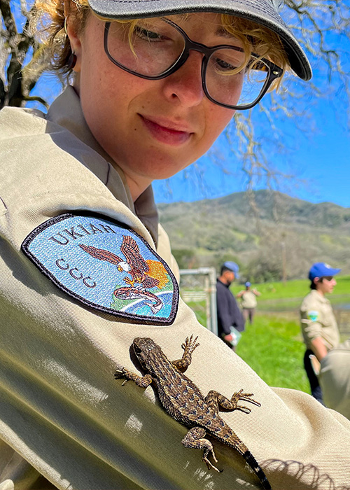 Corpsmember with a small lizard on their arm.