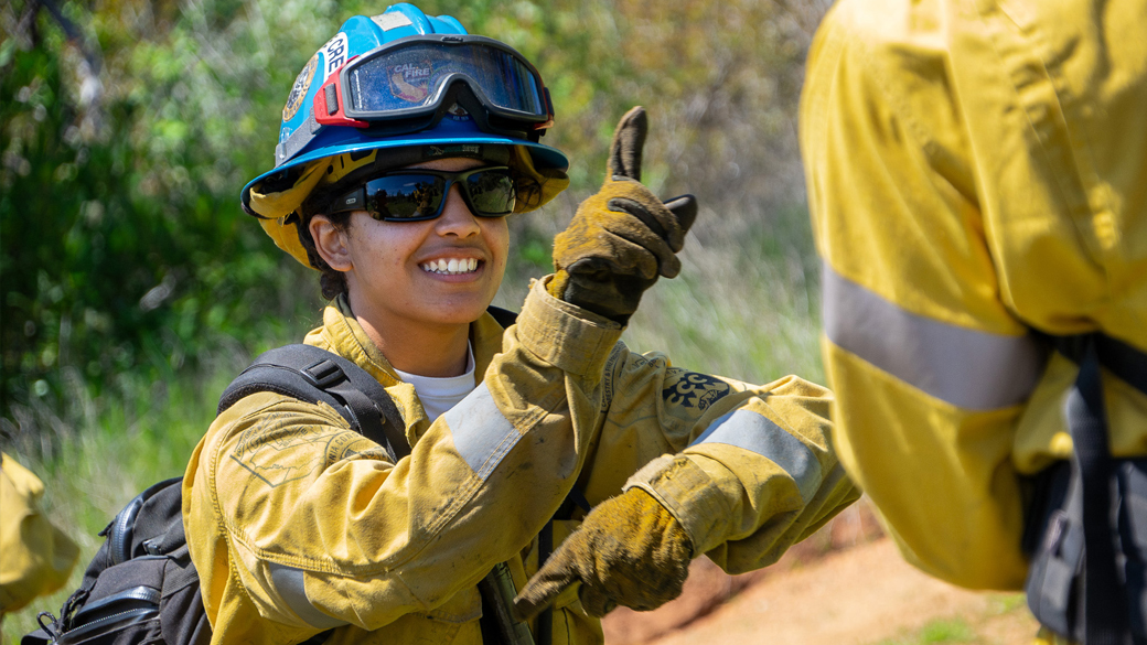 Placer_Fire_CeciliaPierceHandSigns_040324_1040x585 female smiling while giving a practice hand signal in fire gear