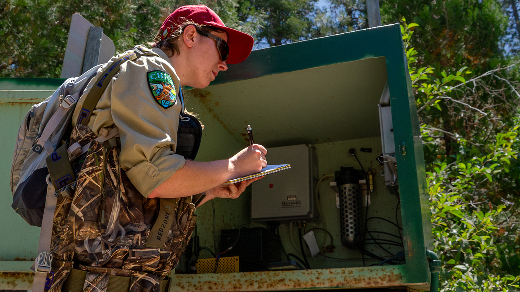 Female in waders and CCC uniform takes notes from a machine on a notepad
