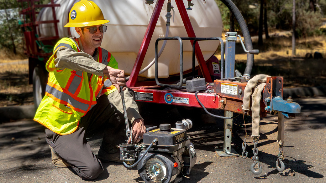Careers_MainMechanic_FixingEngine_1040x585 male holding screw driver turning item on engine in a parking lot