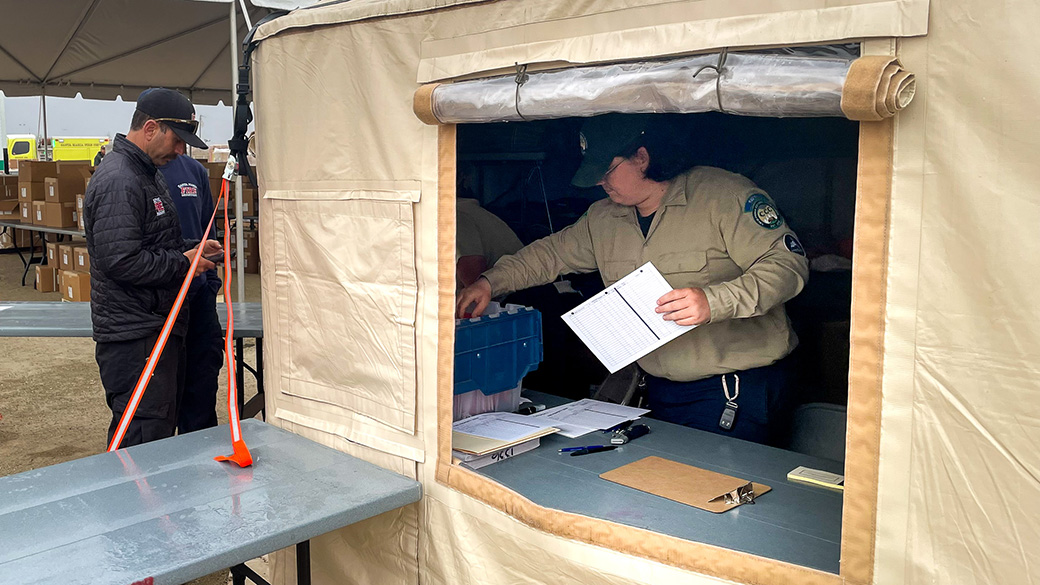 male corpsmember inside a tent holding documents