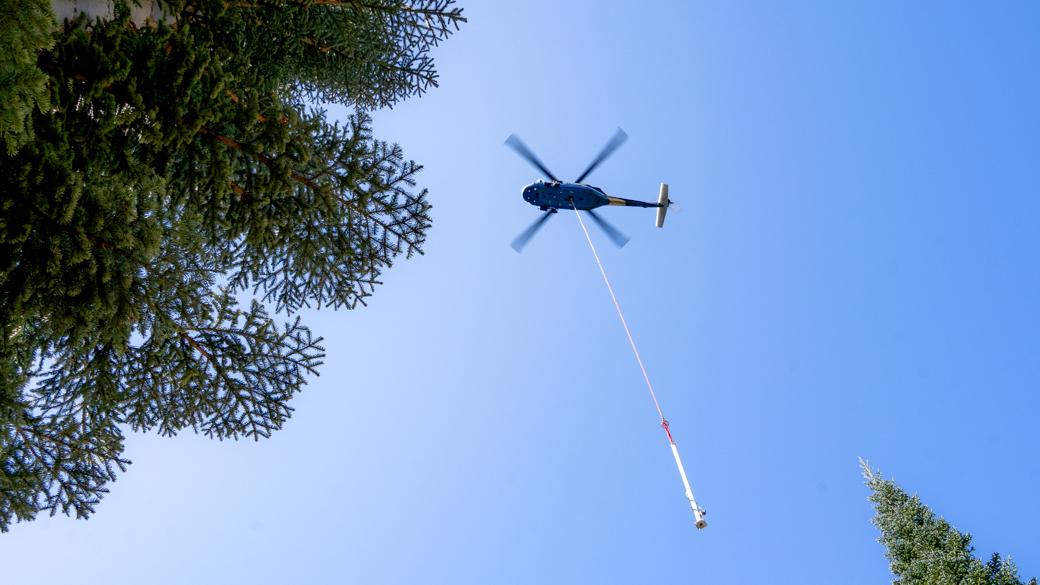 A Black Hawk helicopter lowers a weather station tower into Stanislaus National Forest
