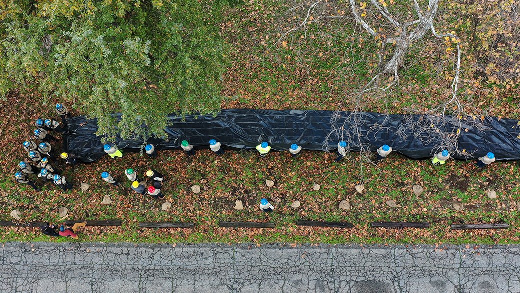 Aerial photo looking down on a crew of Corpsmembers laying out visqueen to practice wave wash protection skills.