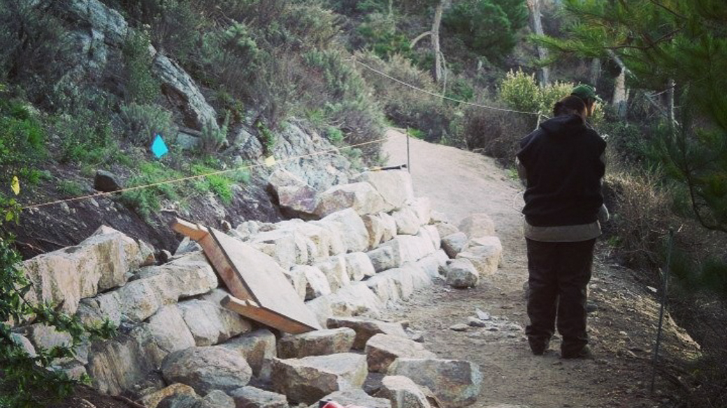 Corpsmembers make progress constructing a rock wall.