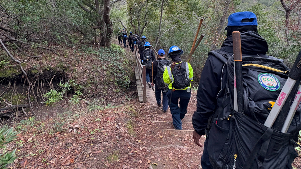 Corpsmembers hike with project gear. 