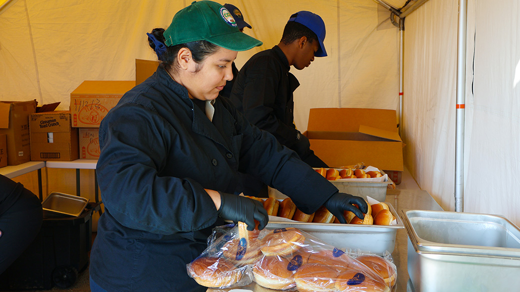 corpsmembers in tent prepare buns for meal service